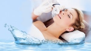 Woman receiving facial treatment, water splash.